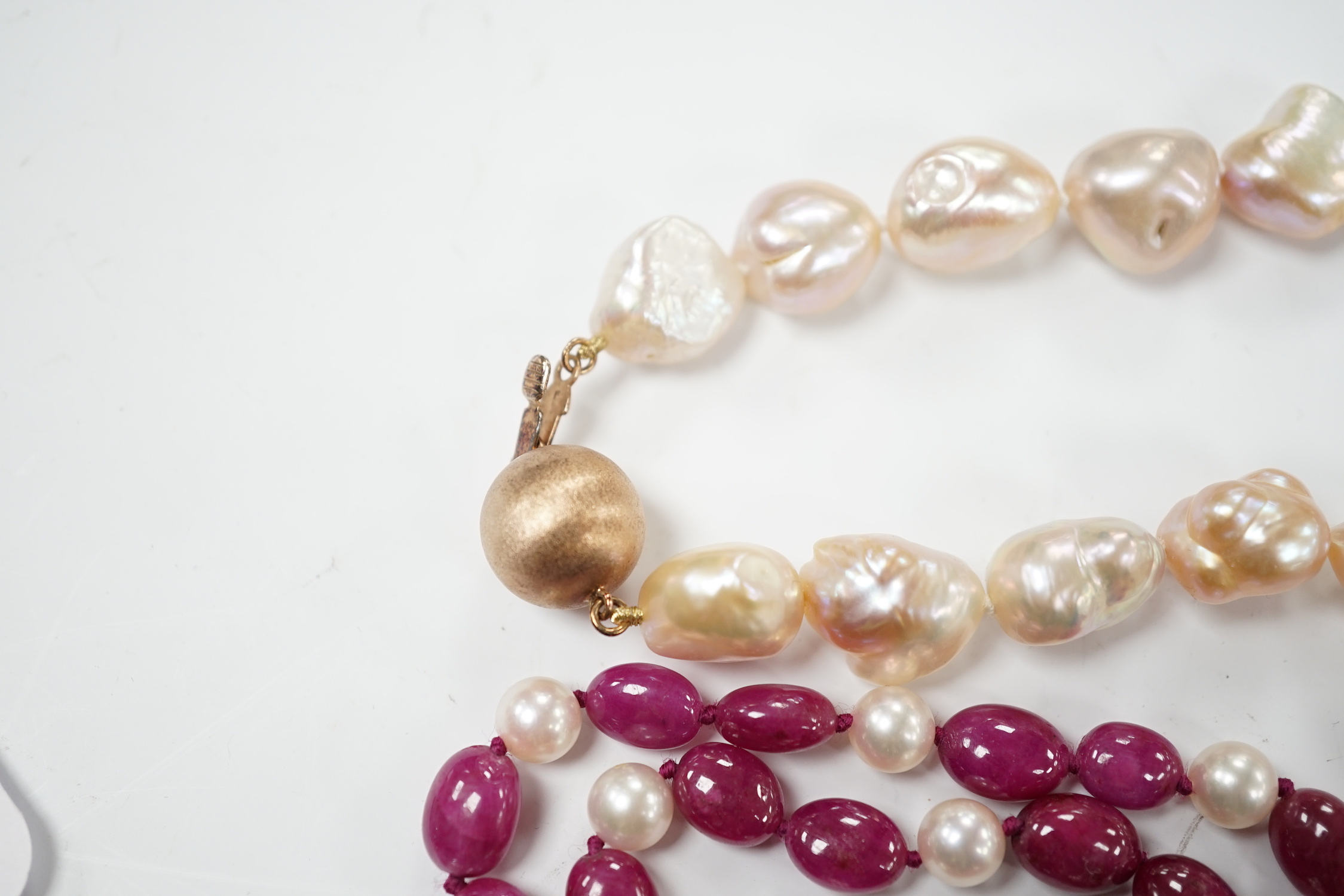 A modern cultured pearl and polished ruby? bead necklace, with two stone diamond chip set 750 clasp, 166cm and a modern baroque freshwater? pearl necklace with 925 clasp.